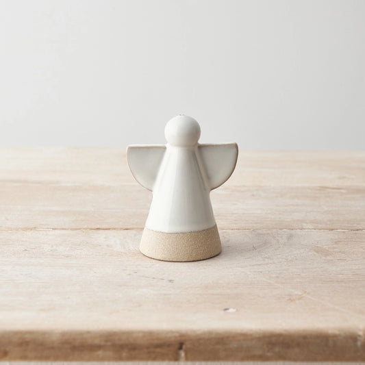 White ceramic angel figurine on a wooden surface with a light gray background