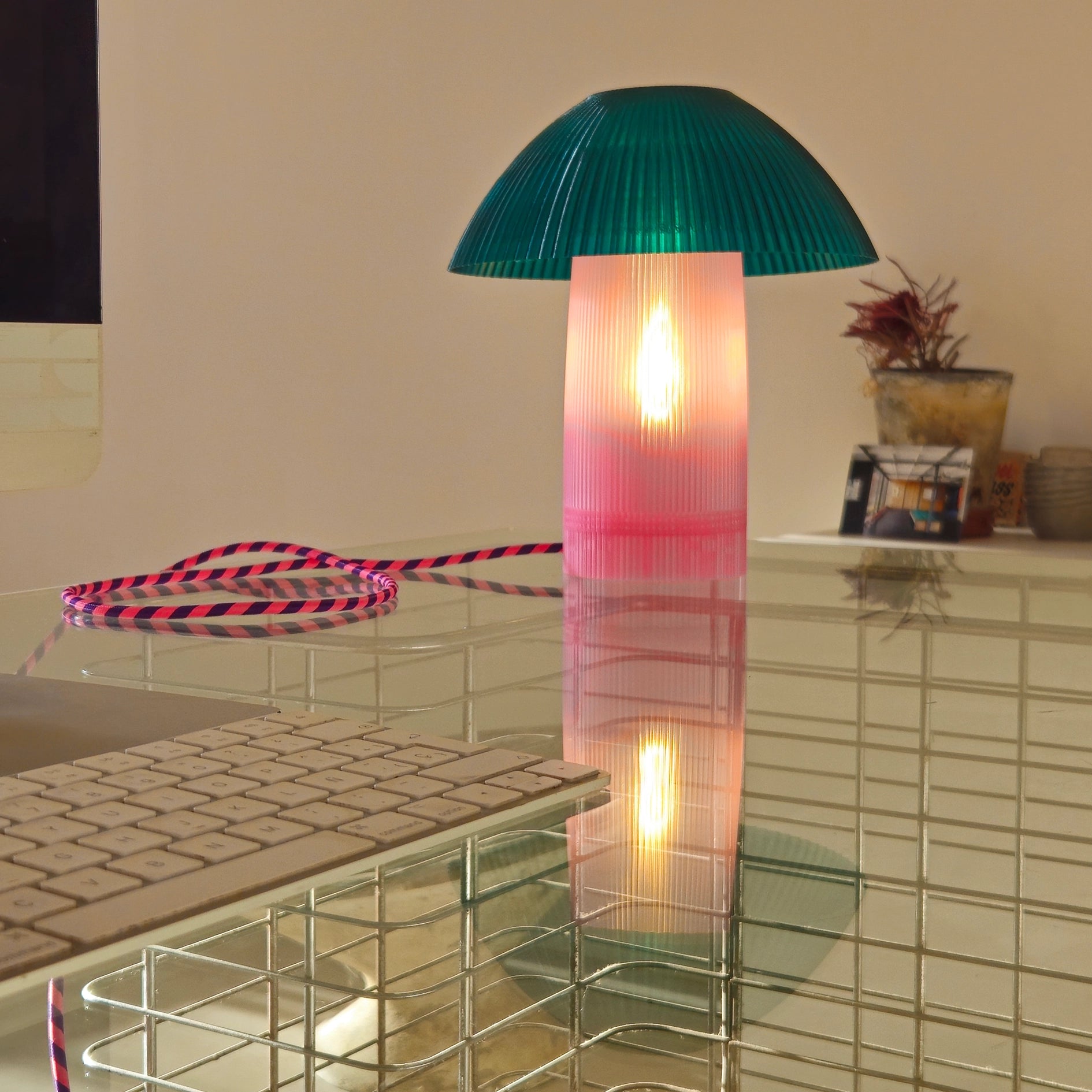 Colorful glass lamp with a light bulb inside on a reflective surface.